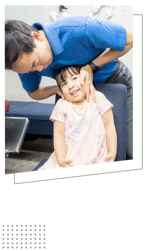 Dr. Zen Matsuda adjusting a smiling young child's neck